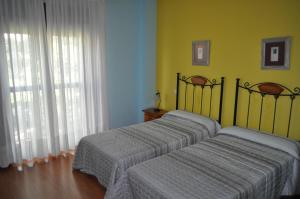 two twin beds in a room with yellow walls at Hotel Puente de Piedra in Zamora