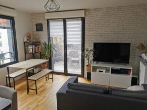sala de estar con sofá y TV de pantalla plana en Appartement calme et lumineux proche Paris, en Asnières-sur-Seine