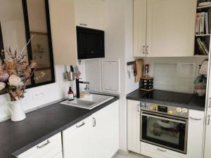 cocina con armarios blancos, fregadero y microondas en Appartement calme et lumineux proche Paris, en Asnières-sur-Seine