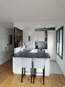 cocina con armarios blancos y encimera negra en Appartement calme et lumineux proche Paris, en Asnières-sur-Seine
