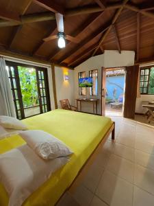 a bedroom with a large bed in a room with windows at Casa Jardim Bangalos in Paraty