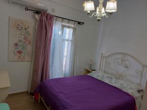 a bedroom with a purple bed and a window at Maritina's house top floor in Kamárion