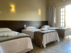 una camera con tre letti con lenzuola bianche di Pousada Recanto Praiano ad Angra dos Reis