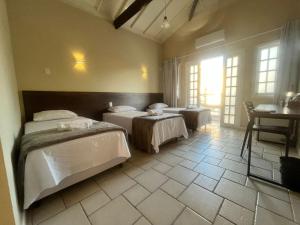 - une chambre avec 2 lits, une table et un bureau dans l'établissement Pousada Recanto Praiano, à Angra dos Reis