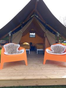 2 camas en una tienda de campaña con sillas naranjas en Safari Lodge Aan de Linge en Tiel