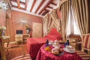 ヴェネツィアにあるディモーラ ドガーレのベッドルーム1室(赤いベッド1台、テーブル、食べ物付)