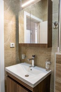 a bathroom with a white sink and a mirror at Home Art Apartments in Skopje