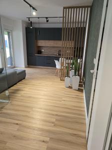 a living room with wooden floors and a kitchen at Apartament Park Trzy Stawy in Katowice
