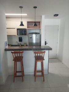 a kitchen with two wooden stools at a counter at Apartamento Novo em Ondina in Salvador