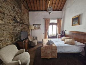 a bedroom with a bed and two chairs in it at Hotel Rural Verde Oliva in Comares