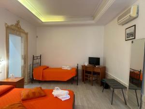 a room with orange beds and a desk and a television at Affittacamere Resalibera in Syracuse