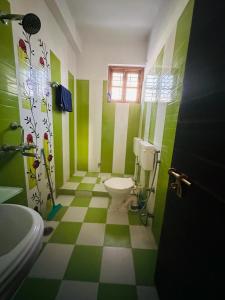 a green and white bathroom with a toilet and a window at Buddha Inn-An Enchanted Garden Villa in Varanasi