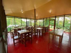 um restaurante com mesas e cadeiras de madeira e janelas em Amazon Açaí Lodge em Letícia