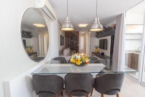 a dining room with a glass table and a mirror at Varandas do Atlântico 306A - Excelente apartamento em condomínio de luxo a beira mar - Piscina climatizada - Academia - (Consultar serviços de roupas de cama e banho) in Bombas