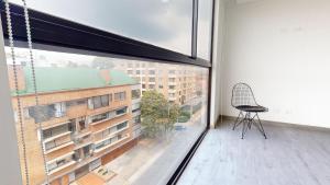 Elle comprend un balcon avec une chaise et une grande fenêtre. dans l'établissement Your Gateway to Bogotá's Best, à Bogotá