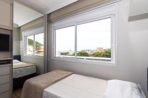a bedroom with two beds and a large window at Varandas do Atlântico 306A - Excelente apartamento em condomínio de luxo a beira mar - Piscina climatizada - Academia - (Consultar serviços de roupas de cama e banho) in Bombas +19 photos