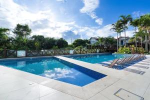 a swimming pool with lounge chairs in a resort at Varandas do Atlântico 306A - Excelente apartamento em condomínio de luxo a beira mar - Piscina climatizada - Academia - (Consultar serviços de roupas de cama e banho) in Bombas