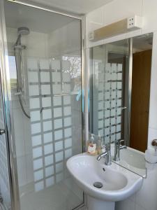 a white bathroom with a sink and a shower at Bryher in Wadebridge