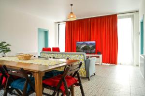 a dining room with a table and red curtains at Villa Capri-Kaprovani in Shekvetili