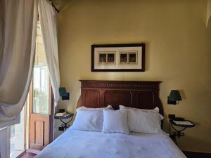 un letto con cuscini bianchi in una camera da letto con finestra di Casa Turchetti a Taormina