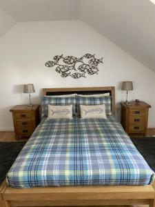 a bed with a plaid comforter and two night stands at Bryher in Wadebridge