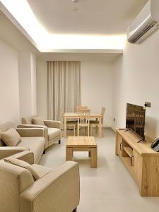 sala de estar con sofás, TV y mesa en Iveria Hotel Apartments en Ḩayl Āl ‘Umayr