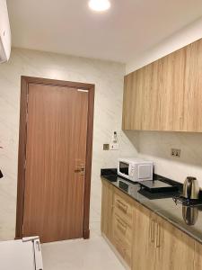 una pequeña cocina con microondas y puerta en Iveria Hotel Apartments, en Ḩayl Āl ‘Umayr