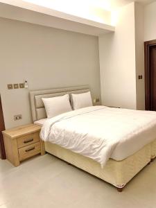 Iveria Hotel Apartments في هيل العمير: غرفة نوم بسرير ابيض كبير وموقف ليلي