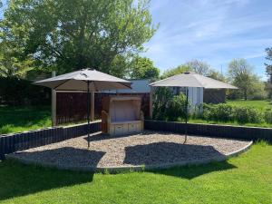 eine Terrasse mit zwei Sonnenschirmen und einem Stuhl im Gras in der Unterkunft Landhus-Sylt  in Archsum