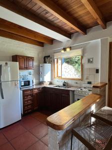 a kitchen with a white refrigerator and a table at Huilen de Bandurrias in San Martín de los Andes