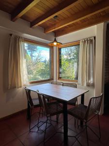 uma sala de jantar com uma mesa e cadeiras e uma janela em Huilen de Bandurrias em San Martín de los Andes