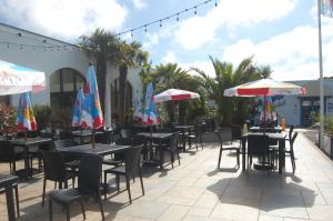 Un patio con mesas, sillas y sombrillas. en Dawlish Warren Welcome family holiday park Fern villa Welcome2Warren South Devon, en Dawlish Warren