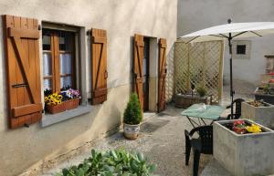 a patio with a table and an umbrella and flowers at Le studio de Josephine in Blars