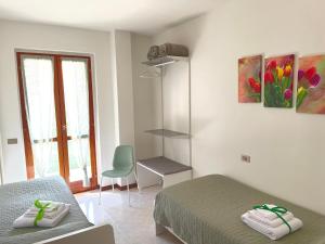 a bedroom with two beds and a chair and a window at Al Parco - Appartamento in Negrar
