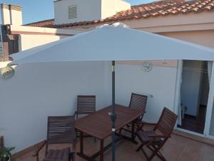 een witte parasol over een tafel en stoelen op een patio bij ÁTICO RESIDENCIAL MARIANA parking privado y piscina in Rincón de la Victoria