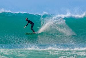 a man riding a wave on a surfboard in the ocean at La petite maison de Celestine in Plonéour-Lanvern