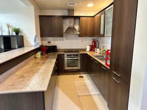 a kitchen with wooden cabinets and a stove top oven at Alken Studio - Amazing Superior Studio with Marvellous Marina View in the Pearl, Doha in Doha
