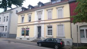 a black car parked in front of a yellow building at Das Düsselapartment in Haan