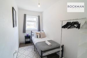 um pequeno quarto branco com uma cama e uma janela em 10A Cromwell Road - Elegant & Modern 3 Bedroom Apartment in Central Grays with 5 beds em Grays Thurrock