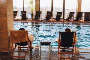 people sitting in chairs in front of a swimming pool at Privat Studio Milmari in Kopaonik