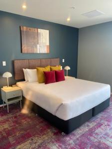 ein Schlafzimmer mit einem großen Bett mit roten und gelben Kissen in der Unterkunft La Quinta by Wyndham Parnell Auckland in Auckland