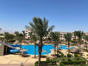 a pool with a slide and palm trees in a resort at Sunset pearl Sahl Hashesh in Hurghada