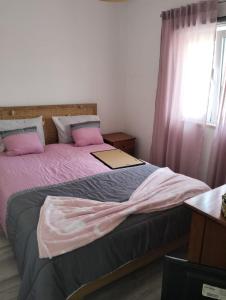 una camera da letto con un letto con lenzuola rosa e una finestra di Casa Alentejana a Mora