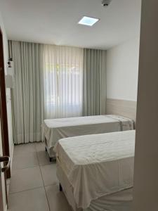 a hospital room with three beds and a window at Condomínio Porto Smeralda in Camacari
