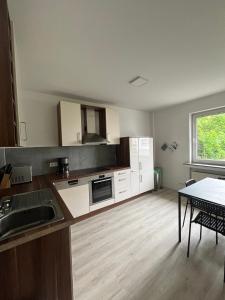 a kitchen with white cabinets and a table and a window at Wohnung für Monteure (Einzelzimmer / Doppelzimmer) in der Nähe von Köln/Bonn/Hennef/Waldbröl in Waldbröl