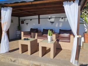un patio con sofás, mesas y dosel en La Casita De Juani, en Santa María de Guía de Gran Canaria