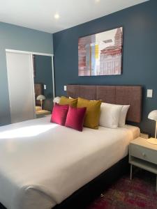 um quarto com uma cama grande com almofadas vermelhas e amarelas em La Quinta by Wyndham Parnell Auckland em Auckland