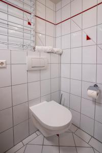 a white tiled bathroom with a toilet and towels at EPA Apartment - Swedish style Souterrain in Rust