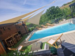 a swimming pool with chairs and umbrellas around it at Aura Lux Holiday Home with Pool in Lopatinec