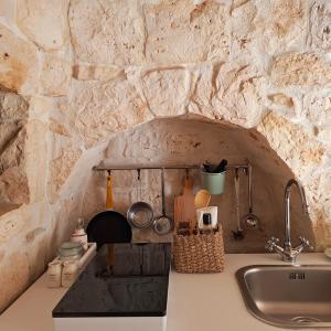 uma cozinha com um lavatório e uma parede de pedra em Residenza Anima Mediterranea em Francavilla Fontana